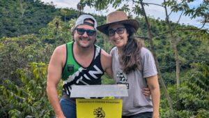 Andrew and Mary at a coffee farm in Colombia with the Armadillo Coffee Roasters sign
